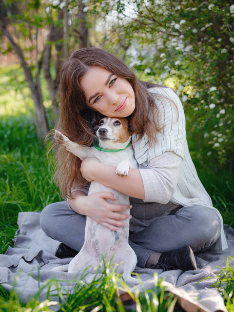 Young woman with her cute Jack Russell Terrier outdoor. Lovely pet. A pleasant spring evening in a happy walking - Foto, imagen