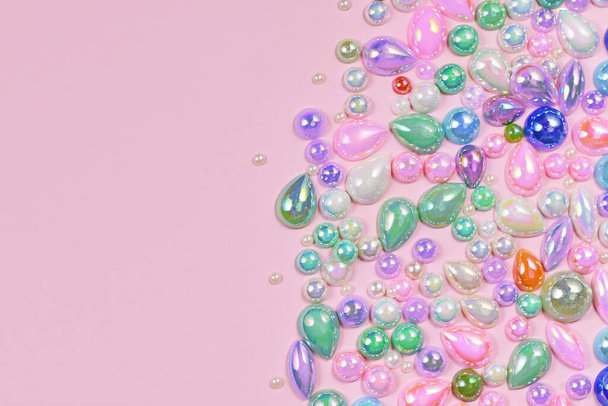 Colorful plastic gemstones on side of pink background with copy space - Foto, Imagem