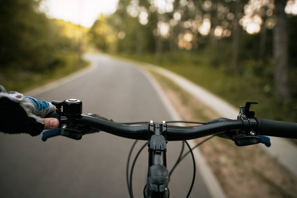 Asfalto carril bici para ciclistas. Concepto de infraestructura para ciclistas. Un ciclista sostiene un manillar de bicicleta con la mano en el guante. - Foto, imagen