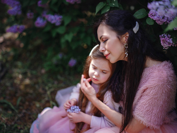 nő a lányával Gyönyörű rózsaszín ruhák szórakozás szabadban tavasszal lilakert. Anya és a gyerek mosolyognak és ölelkeznek. Családi nyaralás és együttlét. Boldog anyák napját!! - Fotó, kép