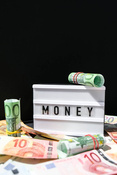 ユーロ紙幣の周りの黒い文字でお金とライトボックスボード。財務の背景。ビジネス、金融の成功とお金の概念を作る。富と繁栄の財政の事業予算。ユーロキャッシュビル - 写真・画像