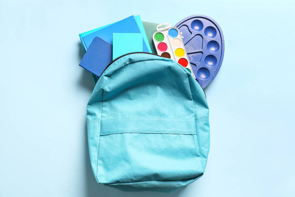 Schulrucksack mit Schreibwaren auf farbigem Hintergrund - Foto, Bild