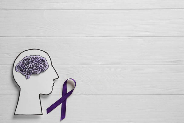 Human head cutout, brain and purple ribbon on white wooden background, flat lay with space for text. Epilepsy awareness - 写真・画像