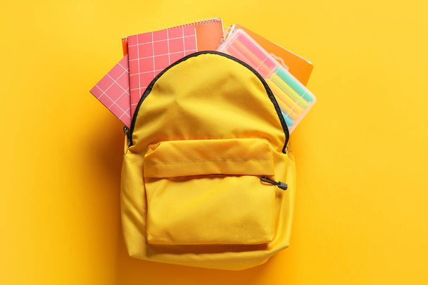 School backpack with stationery on color background - Photo, Image