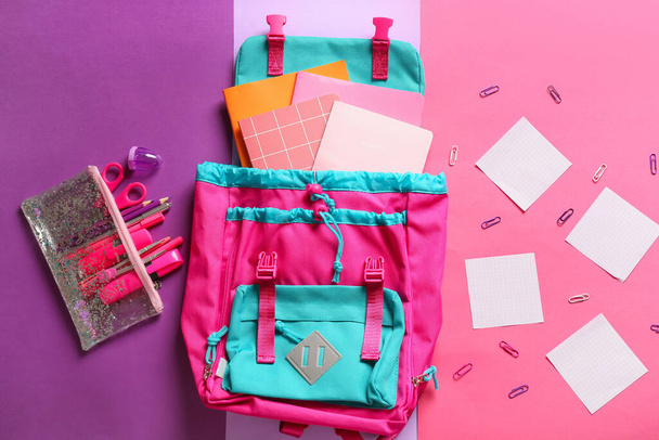 School backpack with stationery on color background - Фото, изображение