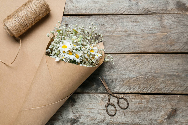 Букет красивих квітів ромашки, ножиць і мотузки на дерев'яному фоні
 - Фото, зображення