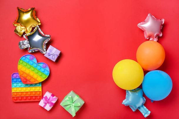 Pop it juguetes inquietos, globos y regalos en el fondo de color - Foto, Imagen