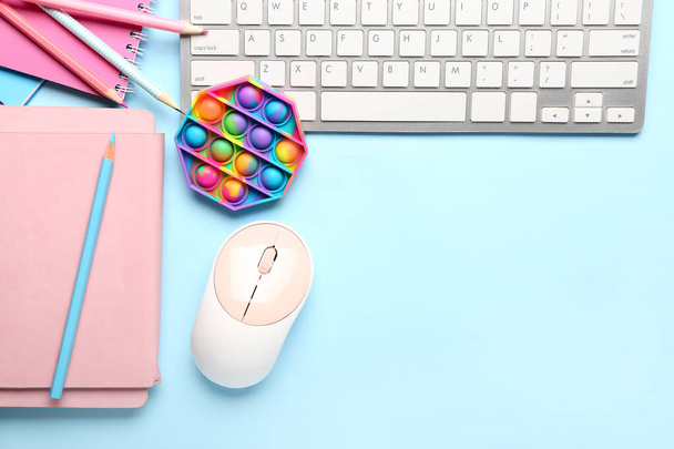 Поп-игрушка, канцелярские принадлежности и клавиатура ПК на цветном фоне - Фото, изображение