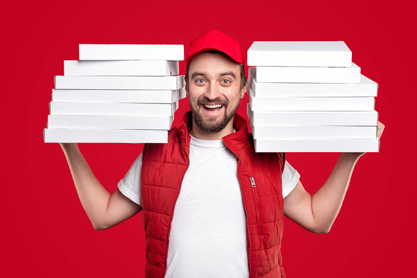 Smiling guy delivering pile of pizza boxes - Foto, Imagen