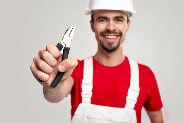 Cheerful worker showing pliers to camera - Zdjęcie, obraz