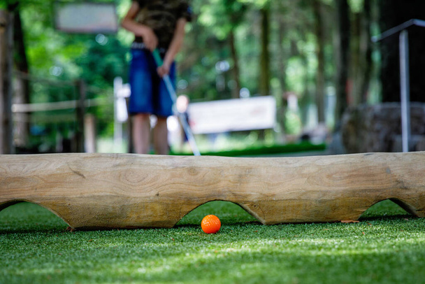 School kid boy playing mini golf with family. Happy child having fun with outdoor activity. Summer sport for children and adults, outdoors. Family vacations or resort. - Photo, Image