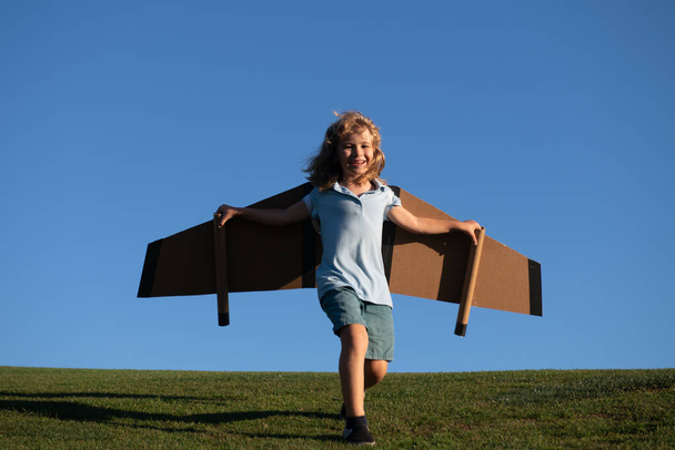 Child boy playing with toy airplane wings. Kids dream of becoming a pilot. Superhero flying. - Foto, afbeelding