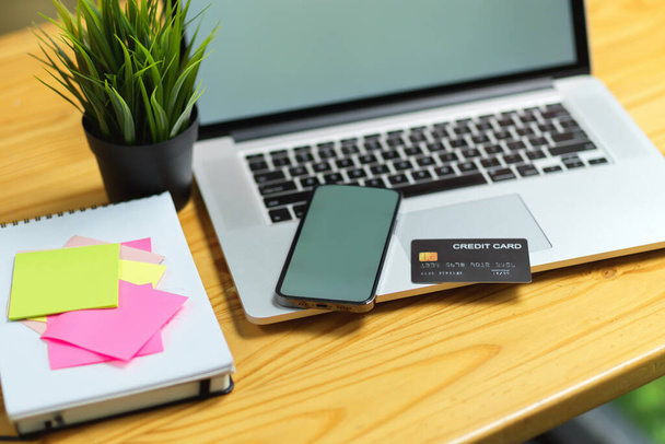 Close-up van mobiele telefoon en laptop leeg scherm mock up met creditcard, plakkerige notities op het bureau  - Foto, afbeelding
