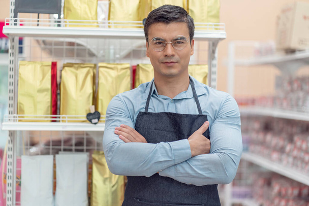 Les propriétaires de petites entreprises, les épiciers, sont confiants et ont des étagères à l'arrière dans l'épicerie.  - Photo, image