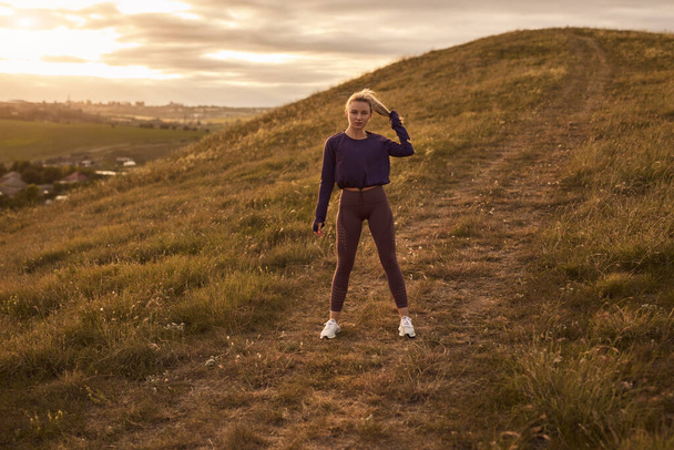 Active woman in sportswear standing on hill - Φωτογραφία, εικόνα