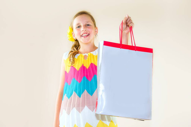 a girl with a smile holds a bag with a gift in her hand , child makes purchases - Foto, afbeelding