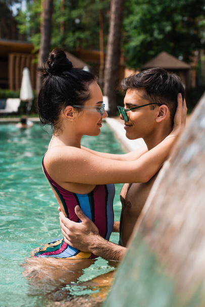 Side view of young couple hugging each other in swimming pool  - Fotó, kép
