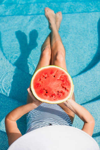 Top view of woman holding watermelon in blurred swimming pool  - Valokuva, kuva