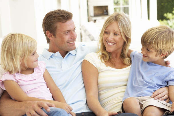 Family sitting in living room smiling - Zdjęcie, obraz
