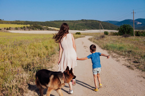 mother and son walk along the rural road to the field - Fotoğraf, Görsel