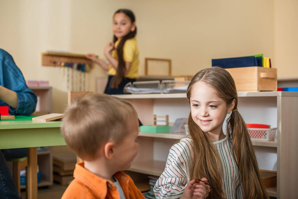 crianças falando em sala de aula perto de professor e menina asiática no fundo borrado - Foto, Imagem