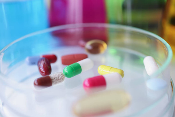 Різнокольорові медичні таблетки лежать на скляній пробірці крупним планом
 - Фото, зображення