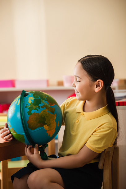 happy asian girl looking at globe in montessori school - Photo, Image