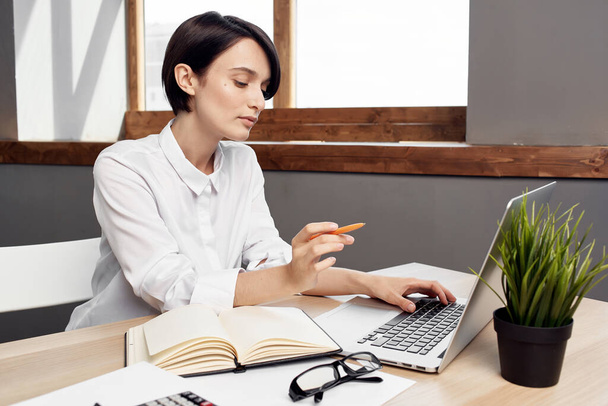 Επιχειρηματίας κάθεται στο γραφείο της μπροστά από το φορητό υπολογιστή γραμματέας Professional - Φωτογραφία, εικόνα