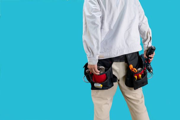 Technicien avec ceinture d'outils autour de la taille sur fond bleu isolé. - Photo, image