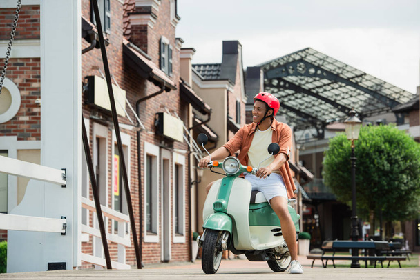 young african american man on scooter near buildings on urban street - Фото, зображення