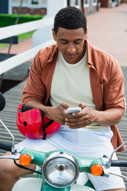 jovem homem americano africano em mensagens scooter no telefone móvel - Foto, Imagem