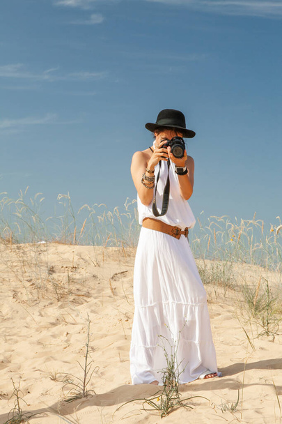 kobieta spacerująca po pustynnym piasku latem i robiąca zdjęcia - Zdjęcie, obraz