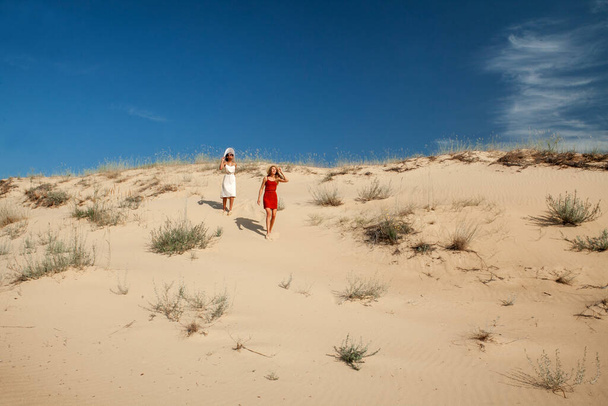 dos mujeres caminan sobre arena caliente en el desierto en el verano - Foto, Imagen