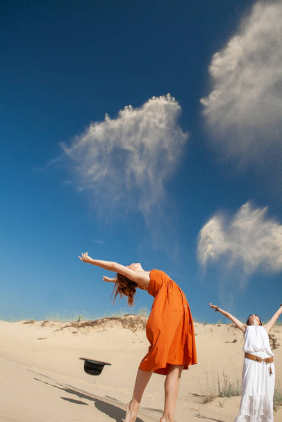 dos mujeres arrojan arena en el desierto en el verano - Foto, Imagen