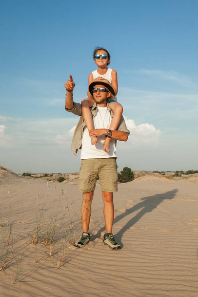 un homme tient un enfant sur ses épaules pendant qu'il est dans le désert en été - Photo, image