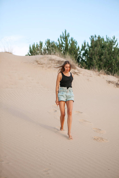 mujer en pantalones cortos pasear por la arena del desierto en el verano - Foto, Imagen
