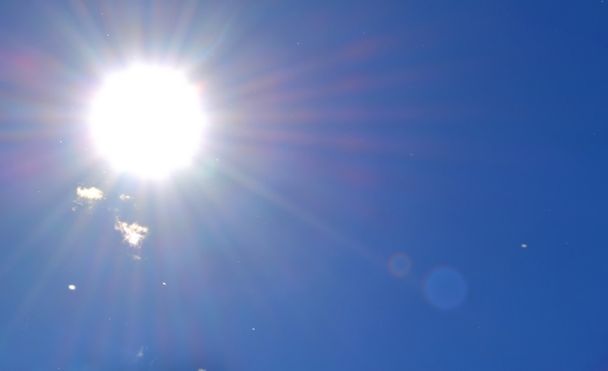 witte wolken over de heldere blauwe hemel met de stralende zon - Foto, afbeelding