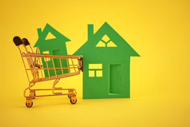Comprar concepto de bienes raíces con casa y carrito de la compra sobre fondo amarillo y espacio de copia gratuita para el texto - Foto, Imagen
