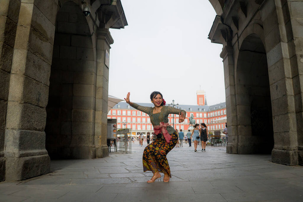 young happy and beautiful Asian woman wearing traditional Balinese kebaya dress - Indonesian girl doing Bali dance on street during holidays travel in Europe - Photo, image