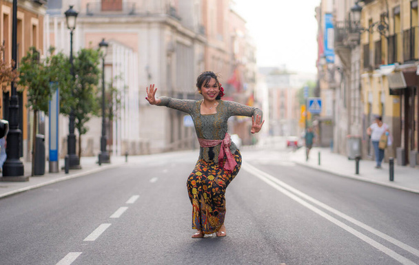 young happy and beautiful Asian woman wearing traditional Balinese kebaya dress - Indonesian girl doing Bali dance on street during holidays travel in Europe - Foto, Imagem