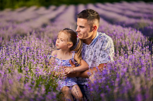 Young father and toddler daughter having fun in a lavender field in full bloom - Фото, изображение