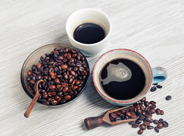 Photo of fresh tasty coffee on light wood table background. Coffee cups and coffee beans. - Fotó, kép