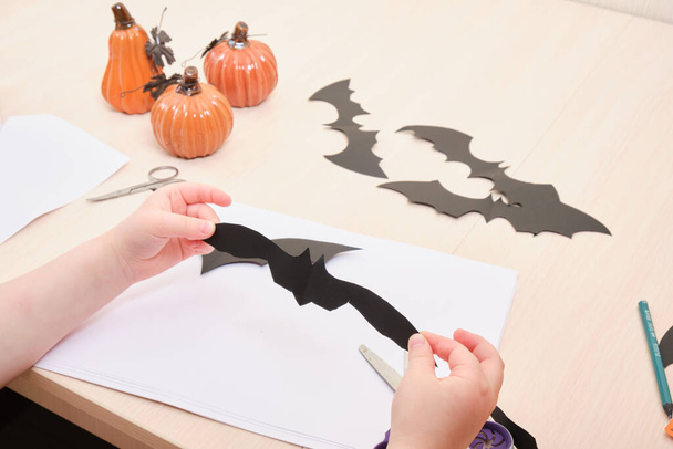 Halloween handmade decor. child cuts a bat out of black paper - Foto, afbeelding