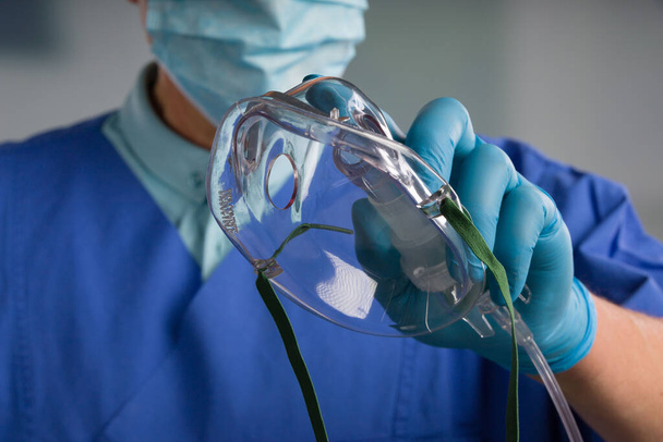 κοντινό πλάνο του χεριού του γιατρού icu με μάσκα οξυγόνου μίας χρήσης για υποστήριξη της αναπνοής  - Φωτογραφία, εικόνα