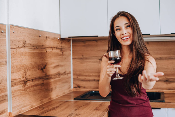 atractiva mujer asiática bebiendo vino en la cocina en casa - Foto, imagen
