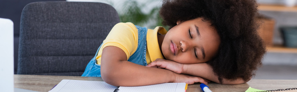 Bambino afroamericano che dorme vicino al taccuino a casa, banner  - Foto, immagini