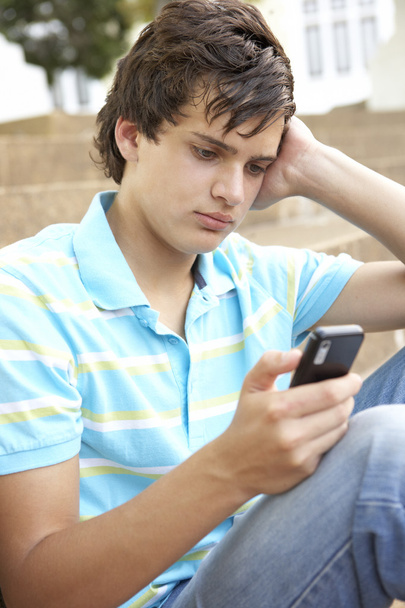 Unhappy Male Teenage Student Sitting Outside On College Steps Us - Valokuva, kuva