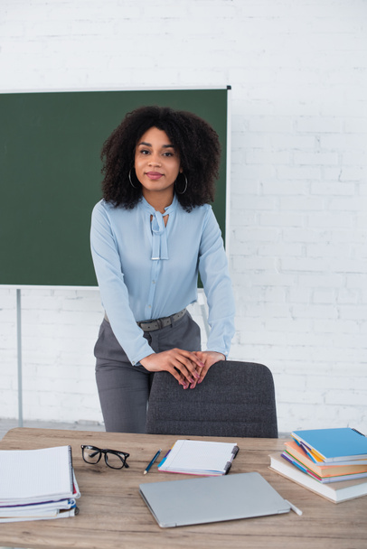 African american teacher standing near laptop and notebooks on table  - Foto, Bild