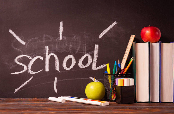 inscription school on a blackboard,  apple , markers, books, pens, textbooks, chalk,  on the table - 写真・画像