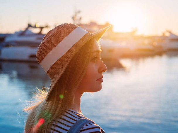 美しい若い女性観光客の夏の日当たりの良い肖像画。日没時に港の周りを歩く - 写真・画像
